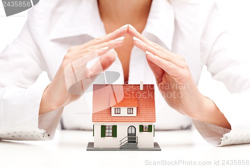 Image of Female hands saving small house with a roof