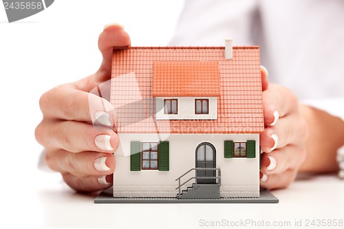 Image of pisture of man and woman hands holding paper house