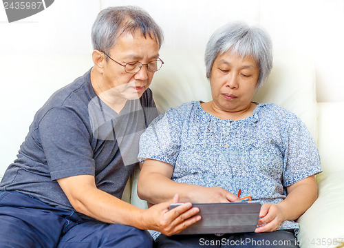 Image of Asian elderly couple using digital tablet