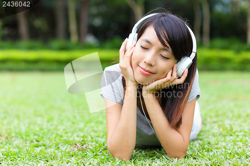 Image of Asian woman listen to song lying on grass