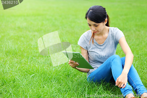 Image of Asian woman using tablet on grassland