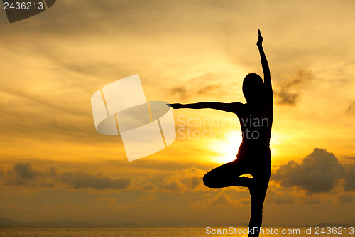 Image of Silhouette of a woman yoga on sea sunset