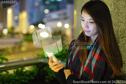 Image of Woman using smartphone in city at night