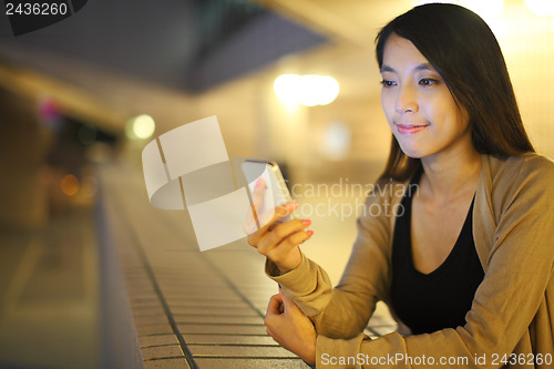 Image of woman using smartphone in city at night