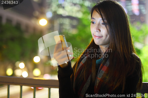Image of woman use mobile phone in city at night
