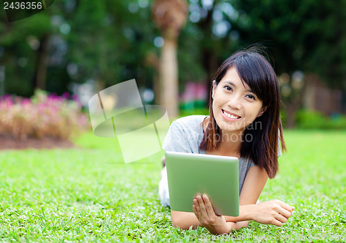 Image of Woman lying on grass with tablet computer