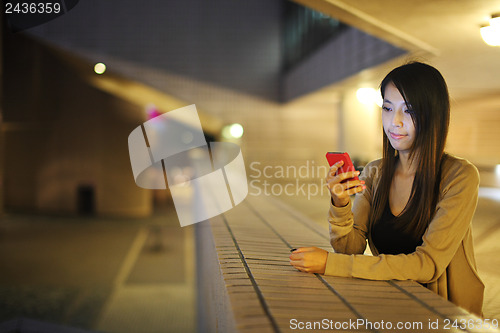 Image of woman using mobile phone in city at night
