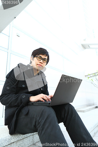 Image of asian man using computer outdoor