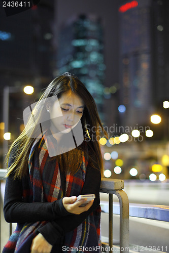 Image of woman use mobile phone in city at night