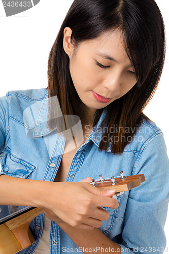 Image of Asian woman tunning ukelele