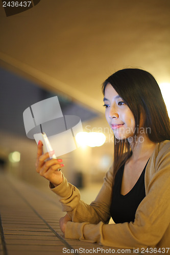Image of woman using phone in city at night 