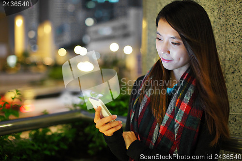 Image of Woman using smartphone in city at night