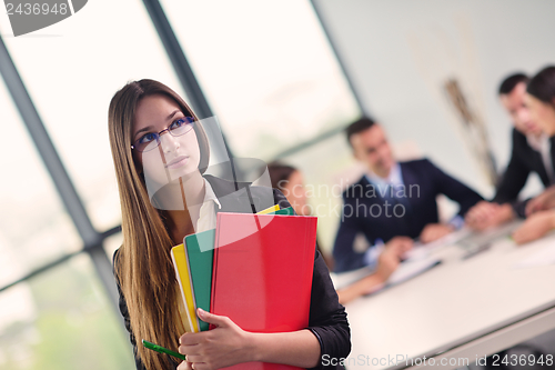 Image of business woman with her staff in background at office