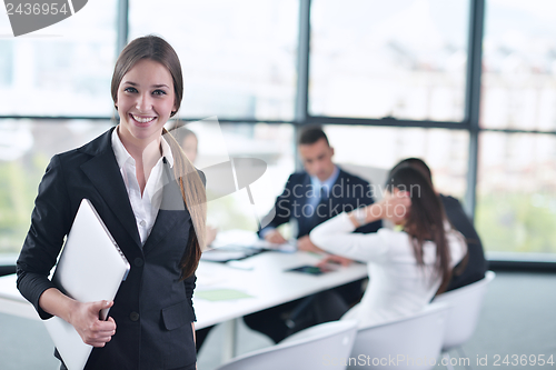 Image of business woman with her staff in background at office