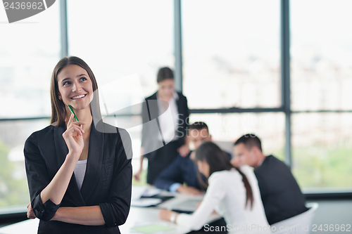 Image of business woman with her staff in background at office