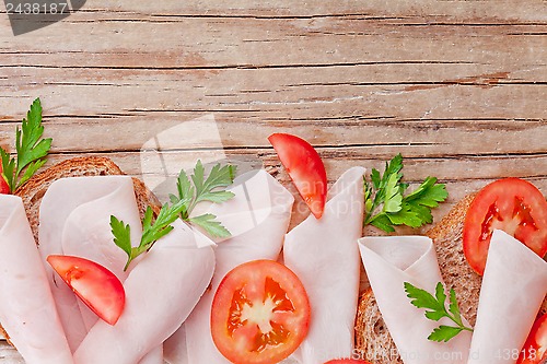 Image of bread with sliced ham, fresh tomatoes and parsley