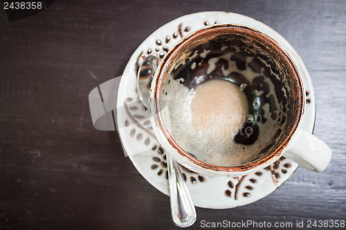 Image of Drinking out of hot cappuccino on table, view from above