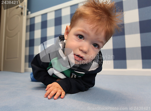 Image of A curious baby boy lying on a floor in room