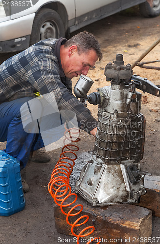 Image of A man cleans the engine taken from the car for overhaul , withou