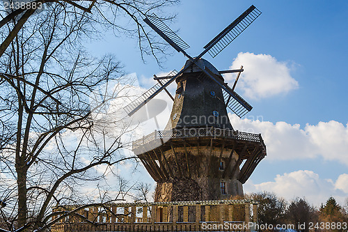 Image of Traditional old european windmil at forest scenery against blue 