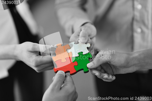 Image of Group of business people assembling jigsaw puzzle