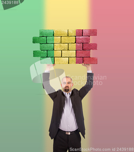 Image of Businessman holding a large piece of a brick wall