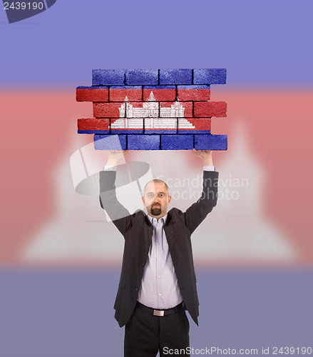 Image of Businessman holding a large piece of a brick wall