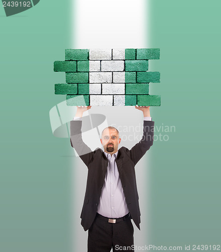 Image of Businessman holding a large piece of a brick wall