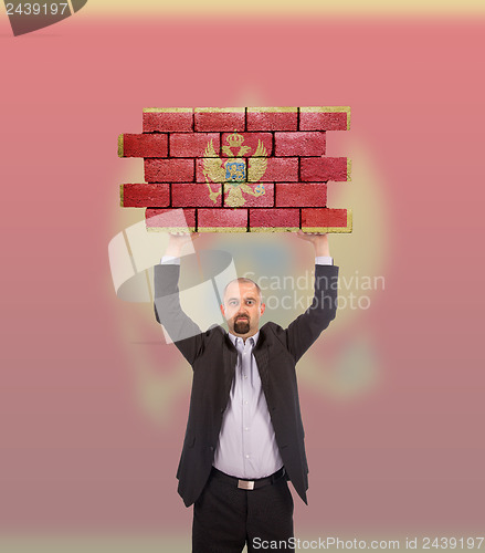 Image of Businessman holding a large piece of a brick wall
