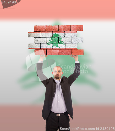 Image of Businessman holding a large piece of a brick wall