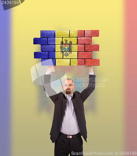 Image of Businessman holding a large piece of a brick wall