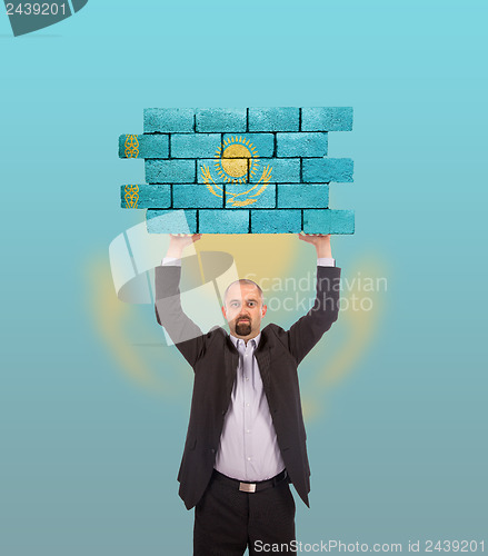 Image of Businessman holding a large piece of a brick wall