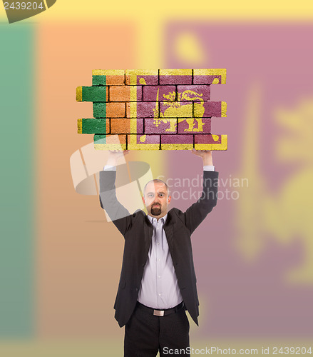 Image of Businessman holding a large piece of a brick wall