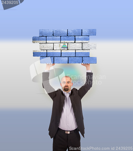 Image of Businessman holding a large piece of a brick wall