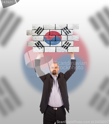 Image of Businessman holding a large piece of a brick wall