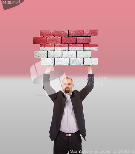 Image of Businessman holding a large piece of a brick wall