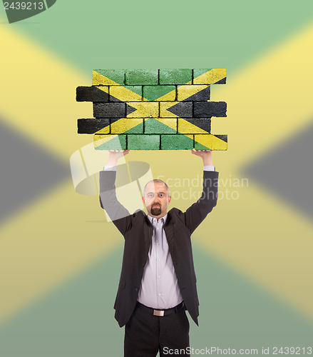 Image of Businessman holding a large piece of a brick wall