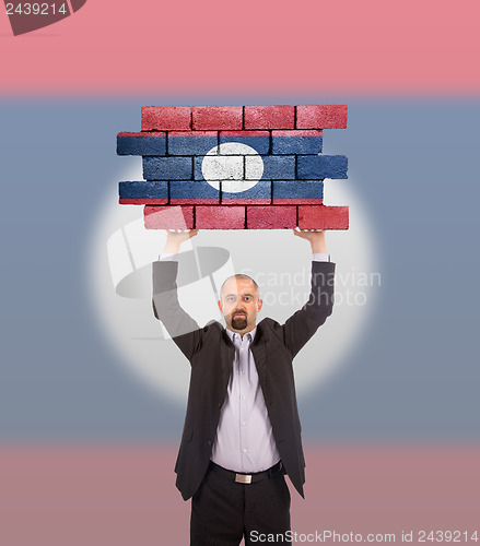 Image of Businessman holding a large piece of a brick wall