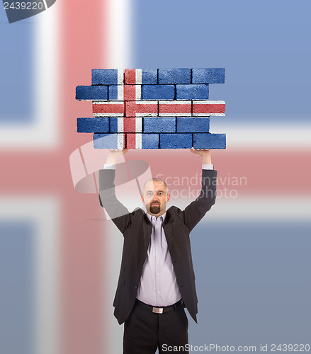 Image of Businessman holding a large piece of a brick wall