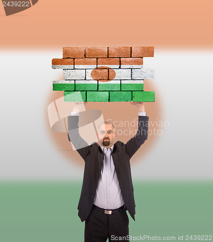 Image of Businessman holding a large piece of a brick wall