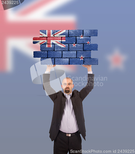 Image of Businessman holding a large piece of a brick wall