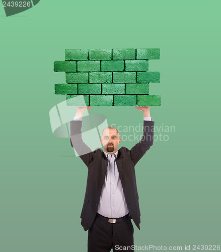 Image of Businessman holding a large piece of a brick wall