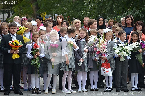 Image of School students stand with flowers in hands on September 1.