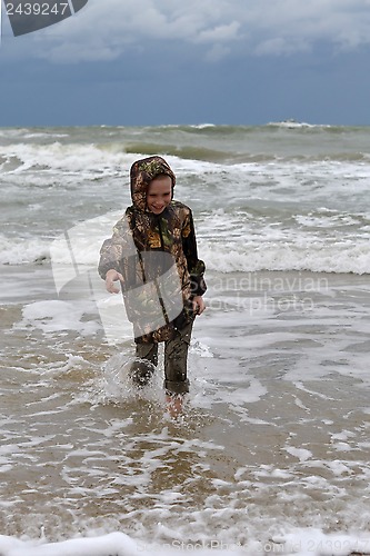 Image of The teenager goes on the seashore in a jacket and barefoot.