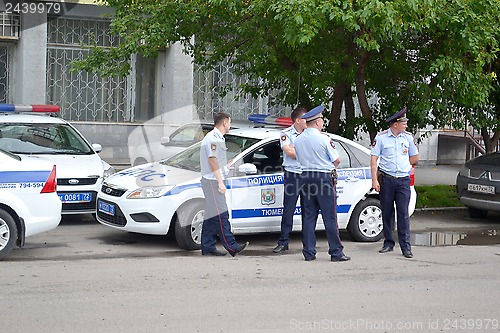 Image of Some police officers stand at the police car