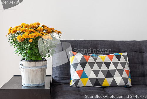 Image of Orange chrysanthemums and bright cushion on a sofa 