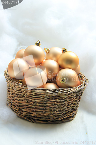 Image of Golden Christmas ornaments in a wicker basket