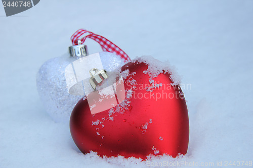 Image of Red and white heart ornaments in snow