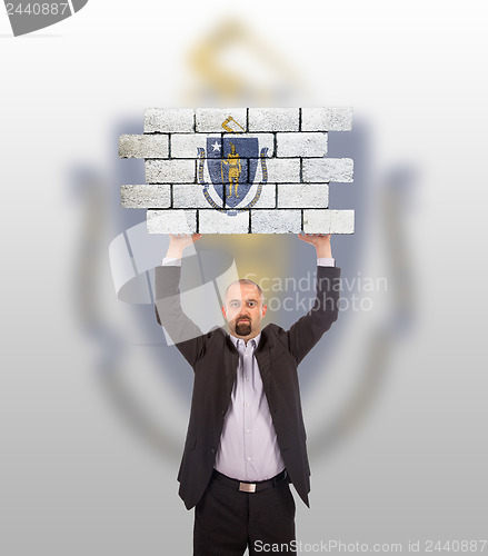 Image of Businessman holding a large piece of a brick wall