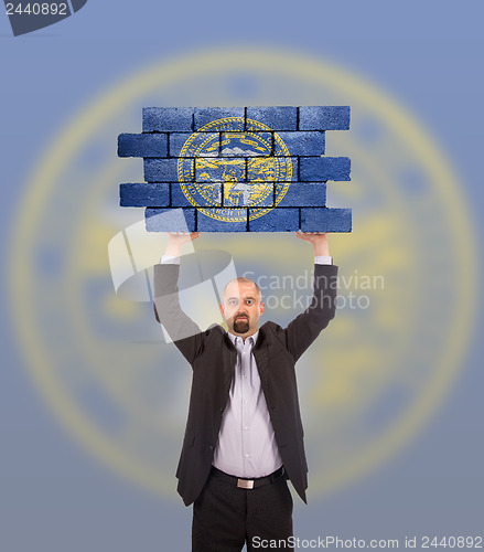 Image of Businessman holding a large piece of a brick wall